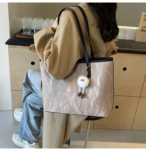 Grande borsa tote beige con texture effetto carta e ciondolo a forma di mostriciattolo