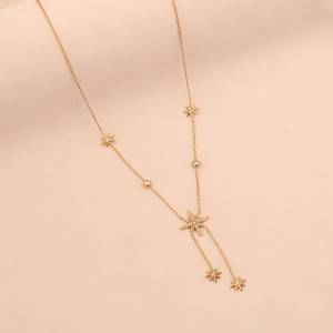 Close-up of golden Y-shaped long necklace with eight-pointed star charms and crystals
