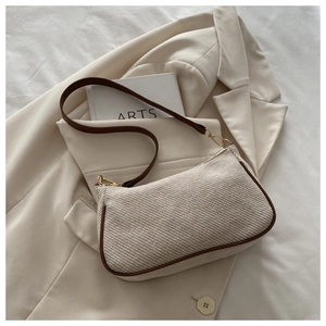 Detail of cream woven shoulder bag with brown leather trim and golden metal buckles