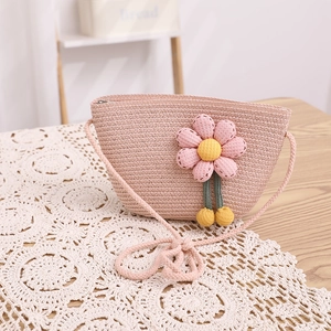 Détail d'un sac bandoulière en paille rose avec fleur et fermeture éclair sur dentelle