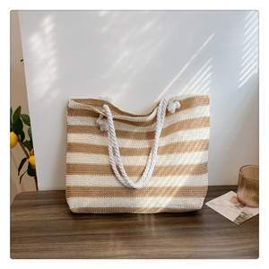 Close-up of a large woven straw tote bag with natural and white stripes and rope handles
