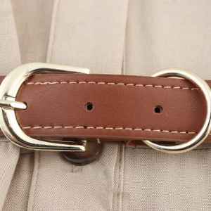 Detail of brown leather belt with gold metal buckle on beige linen dress fabric