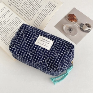 Detail of navy plaid quilted makeup bag with mint green zipper cord and fabric label