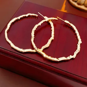 Grandes boucles d'oreilles créoles dorées avec texture martelée sur boîte en bois
