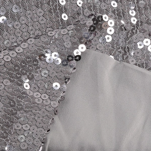 Gros plan détaillé de paillettes argentées sur le tissu d'une robe de soirée violette