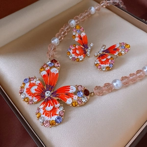 Detailed shot of butterfly jewelry set with orange enamel and colorful crystals