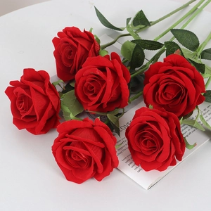 Artificial velvet red roses bouquet on white table with decorative paper script