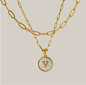 Vue détaillée du collier double rang doré avec pendentif lettre V sur nacre blanche