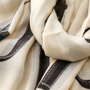 Macro shot of cream-colored linen-feel scarf showing soft texture and artistic grey patterns