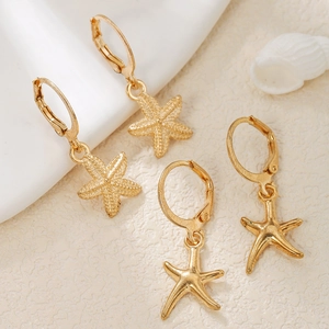 Detail shot of golden starfish earrings with matte and smooth textures on stone base