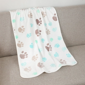 Detail of soft white flannel pet blanket with multi-color paw prints on a gray sofa