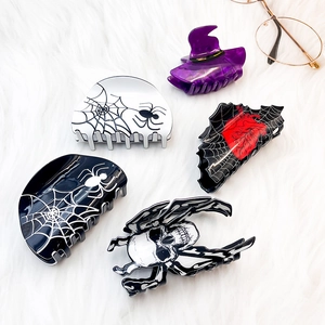 Halloween claw clips set with spider web and witch hat designs on white plush background