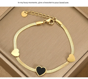 Detail of gold snake chain bracelet with heart charms on brown jewelry box