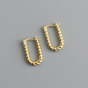 Detailed view of U-shaped gold earrings with intricate twisted texture and metallic finish