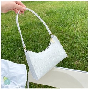 Detail of white crocodile pattern shoulder bag with gold zipper outdoors