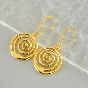Minimalist gold spiral drop earrings with double vortex design on textured backdrop