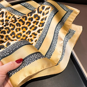 Detailed macro view of leopard print silk scarf texture and smooth satin material finish