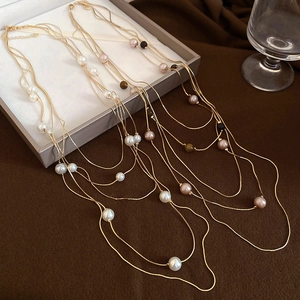 Detail of layered gold-tone necklace featuring tiger eye stones and faux pearls