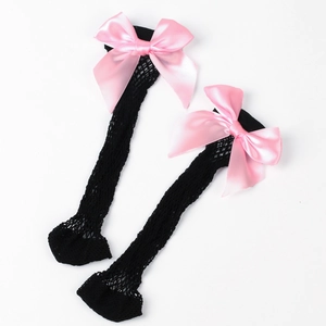 Close-up of black mesh knee-high socks with large decorative pink satin bows on top
