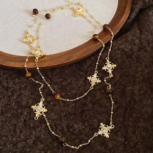 Detail of vintage gold tiger eye stone necklace with crystal flower and cross charms