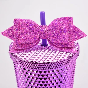Close-up of a glittering purple bow decoration on a diamond texture cup lid with straw