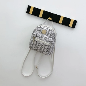 Detailed close-up of a small snakeskin pattern backpack hanging on a modern wall hook