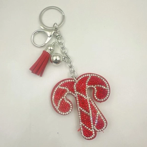 Detailed view of rhinestone-studded red letter T keychain with silver bell and red tassel