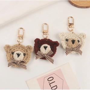Detailed close-up of handmade crochet bear charms with plaid bows and golden clasps