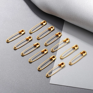Detailed view of 11 pieces of 18K gold-plated steel safety pins on a textured background