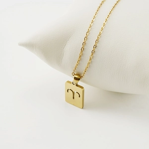 Detailed view of square 18K gold Aries zodiac pendant on a white jewelry cushion