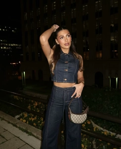 Détail d'un ensemble en jean bleu foncé avec gilet sans manches et pantalon large