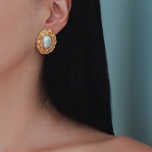 Vintage gold spiral frame pearl earrings worn by a model in a side-profile view