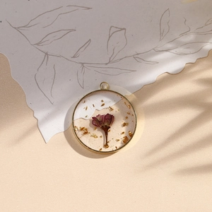 Handmade resin floral pendant with purple dried flowers and gold leaf in a gold frame
