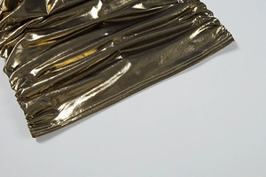 Détail du tissu métallique doré brillant avec un design froncé élégant et couture précise