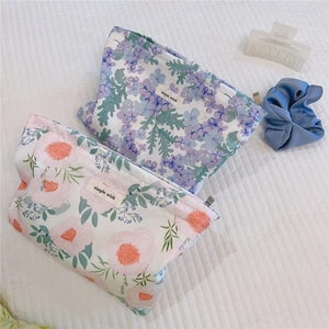 Detailed view of floral cotton makeup bags with simple wish labels on quilted background