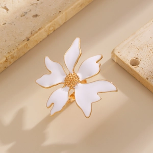 Détail d'une bague fleur dorée avec pétales en émail blanc sur un support en pierre naturelle