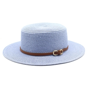 Détail du tissage d'un chapeau de paille bleu clair avec ruban en cuir brun et boucle or