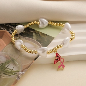 Beaded gold and pearl heart bracelet featuring pink ribbon butterfly charm on soft fabric