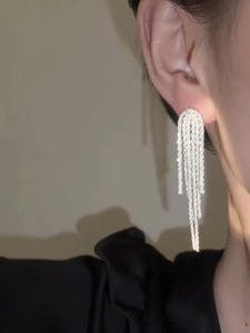 Detail of silver tassel earrings on model with long shimmering metallic fringe