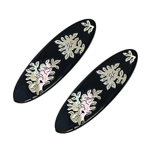 Elegant black oval hair clips set with mother-of-pearl floral inlays on white backdrop
