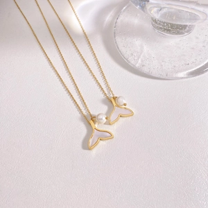 Golden mermaid tail necklace with freshwater pearl and shell inlay on white texture