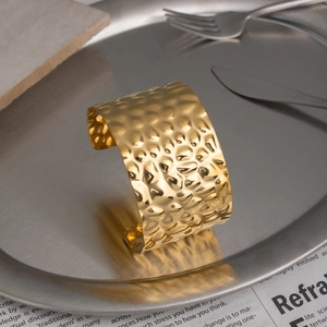Macro detail of wide hammered 18K gold plated stainless steel cuff on vintage background