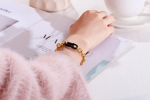 Gros plan d'un bracelet gourmette en résine dorée et noire porté au poignet dans un décor chic