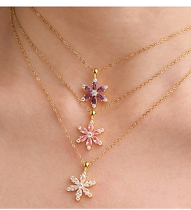 Detailed view of three layered gold necklaces with purple and pink zircon flower pendants