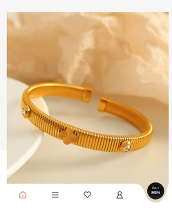 Close-up of golden grooved clover bracelet with sparkling rhinestones on fabric
