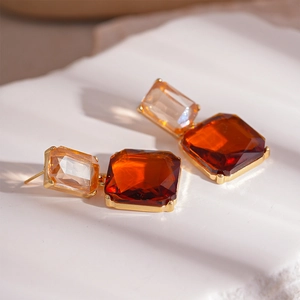 Gros plan de boucles d'oreilles carrées avec cristaux champagne et ambre sertis d'or