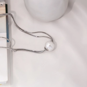 Detailed close-up of a large white pearl pendant on a sleek silver snake chain necklace