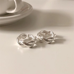 Macro detail of two intertwined silver twist rings on a minimal ceramic background