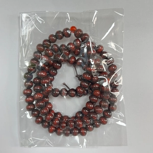 Detailed view of 108 dark red sandalwood Buddhist beads in a protective packaging
