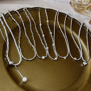Detail of silver heart tassels, pearls, and crushed beads necklaces on a golden plate
